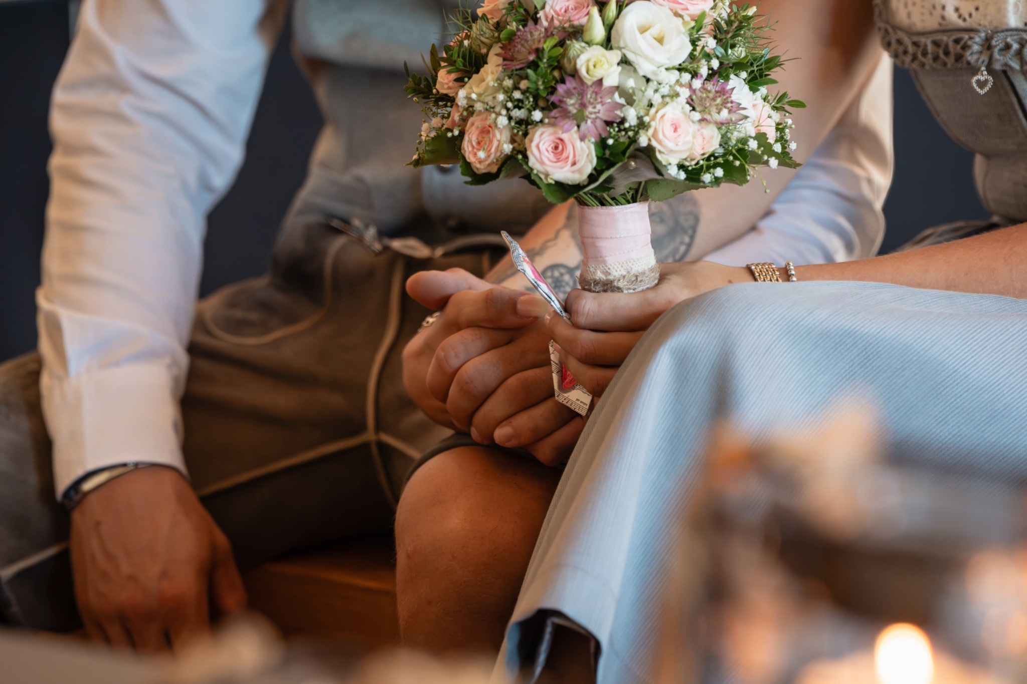 Detailaufnahme von Brautstrauß und ineinanderliegenden Händen des Brautpaares bei einer Trachtenhochzeit
