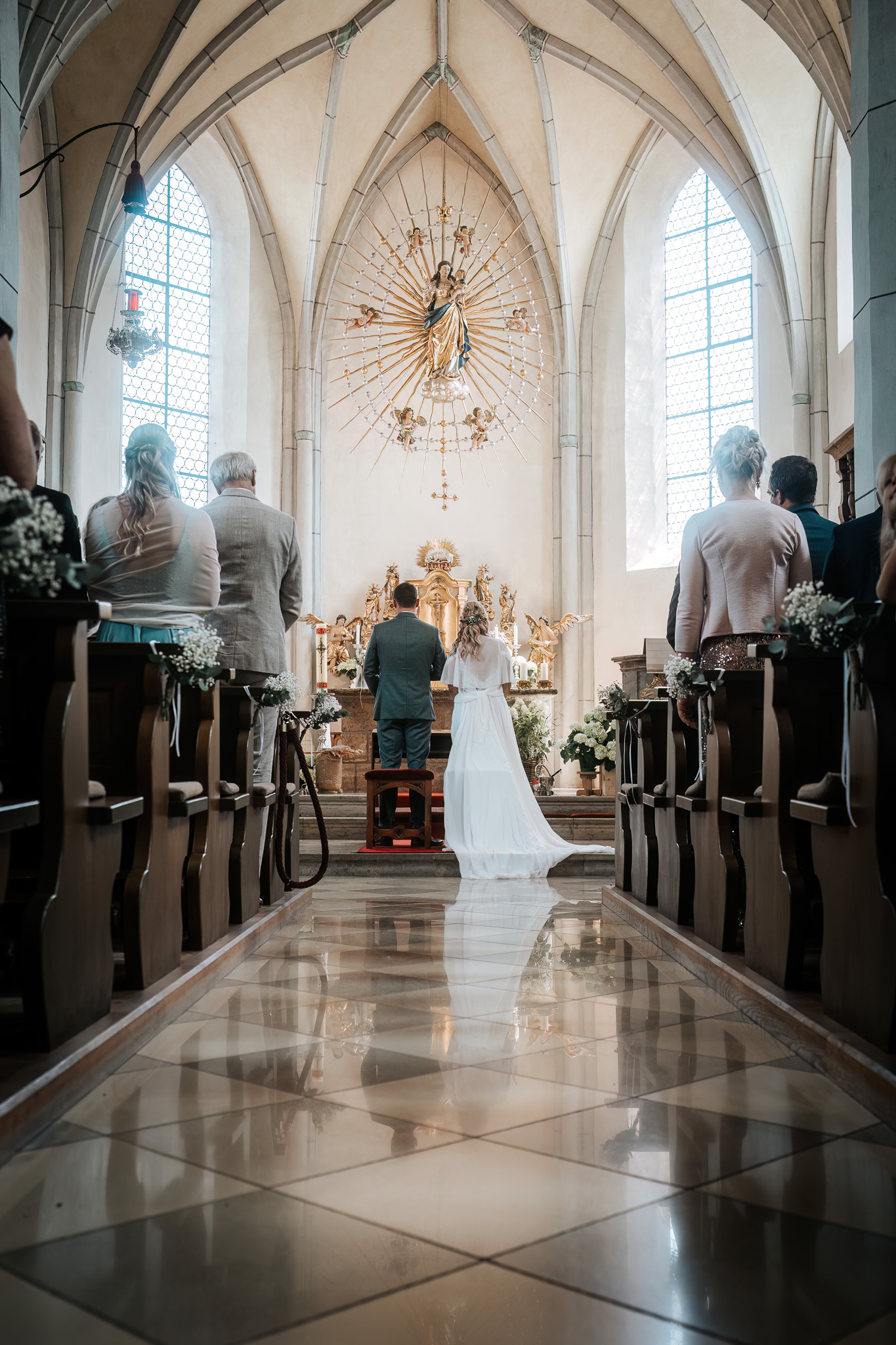 Brautpaar und Gäste im hellen Kirchenschiff von Anger