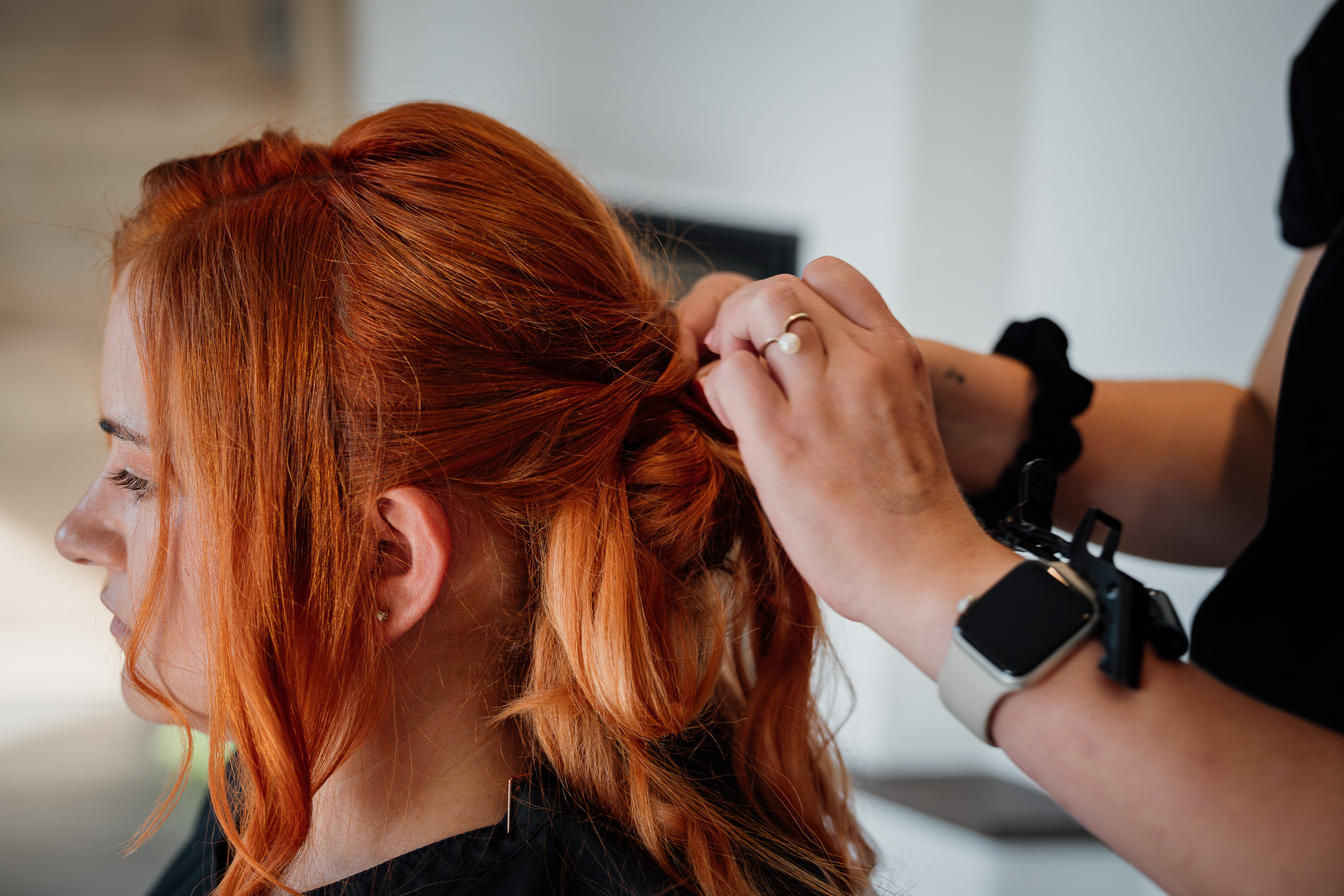 Die langen roten Haare der Braut werden für die Hochzeit Schritt für Schritt hochgesteckt.