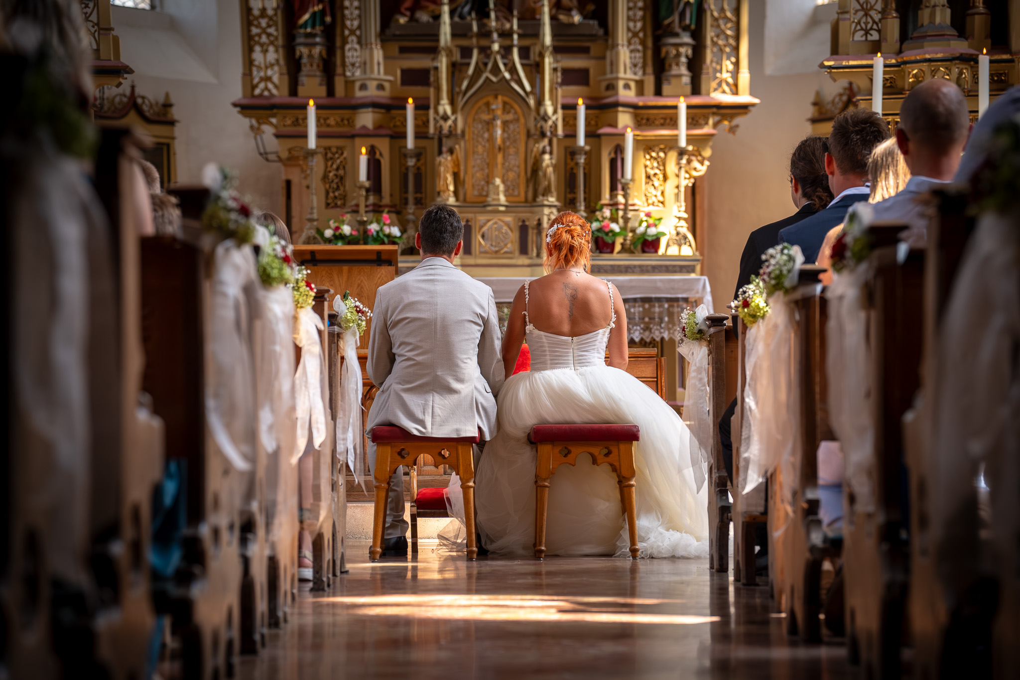 Das frisch vermählte Brautpaar sitzt nach dem Ringtausch vor dem Altar.