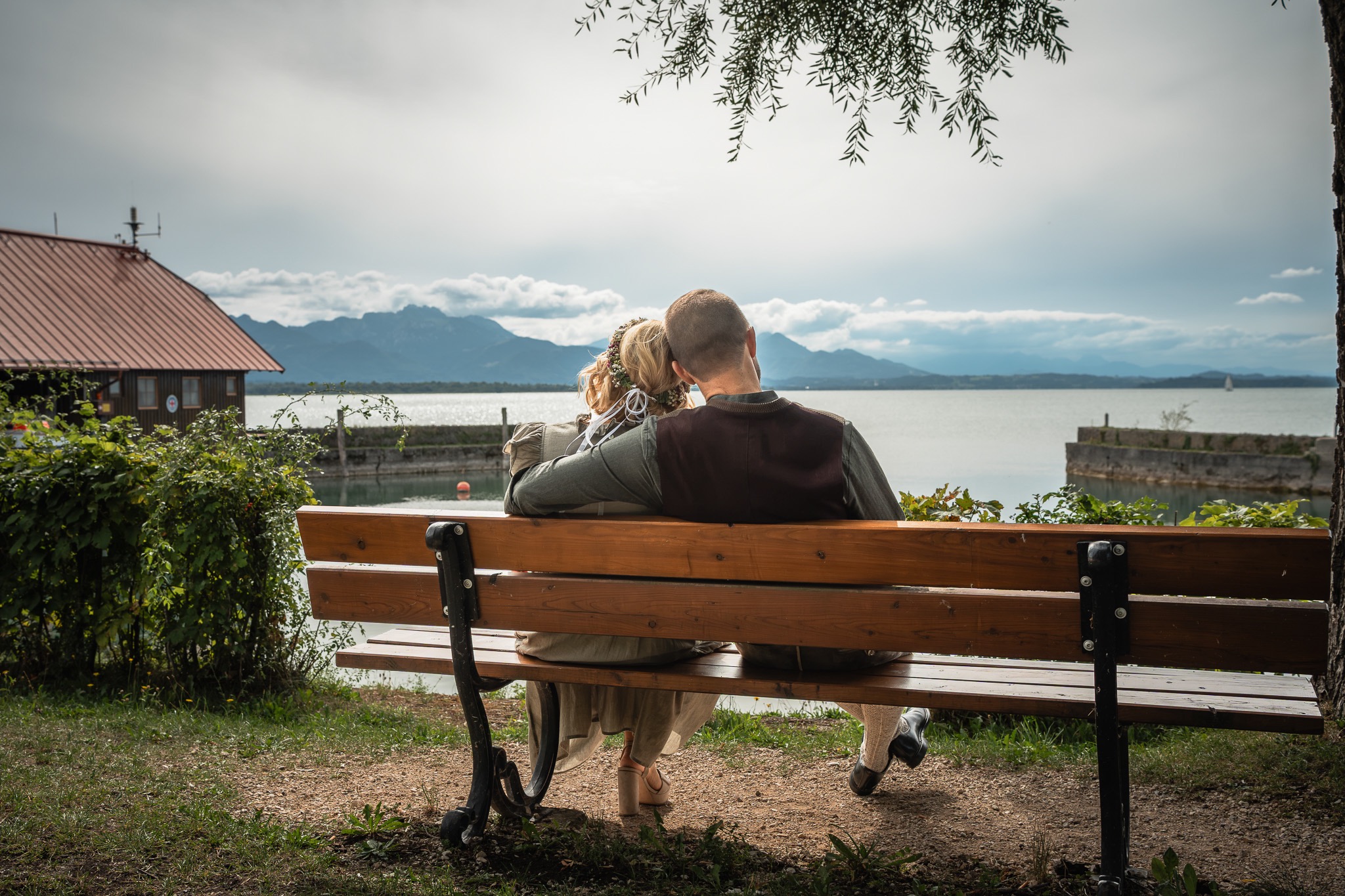 Brautpaar am Chiemsee bei Chieming Brautpaar auf einer Bank am Chiemsee bei Chieming mit Blick auf die Chiemgauer Alpen